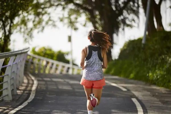 亚洲年轻女子在公园里慢跑的后视镜 图库图片
