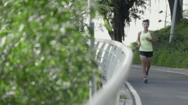 Genç Asyalı bayan sporcu parkta koşuyor.