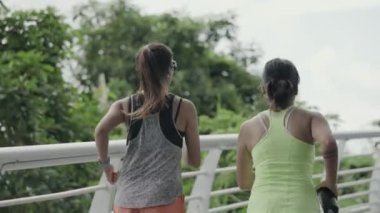 rear view of two young asian women female athlete running jogging exercising outdoors in park