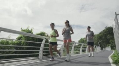 three young asian people man and woman running jogging exercising outdoor in park