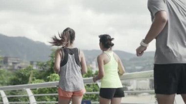 rear view of three young asian people man and woman running jogging exercising outdoor in park