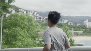 Parkta koşan Asyalı genç adamın yan görüntüsü