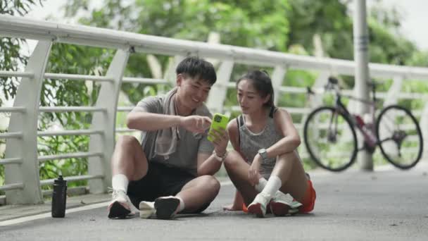 Joven Asiático Pareja Sentado Suelo Parque Mirando Celular Charlando Hablar — Vídeo de stock