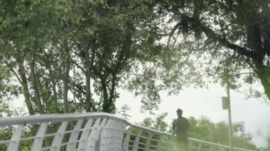 Genç Asyalı adam parkta koşuyor.