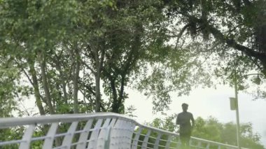 Genç Asyalı bir adam parkta koşuyor.