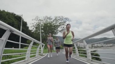 Parkta koşan üç Asyalı gencin arka görüntüsü