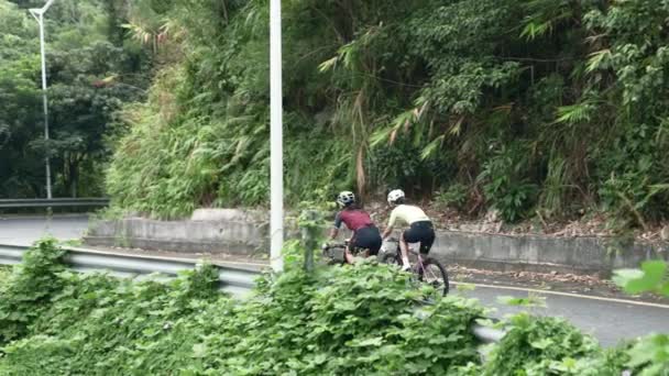 年轻的亚洲骑单车者在乡村道路上沿着弯道骑行的后视镜 — 图库视频影像