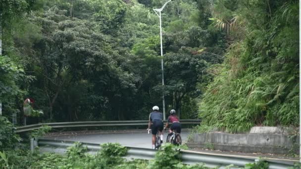 Bakifrån Unga Asiatiska Cyklister Rider Runt Kurva Landsvägen — Stockvideo