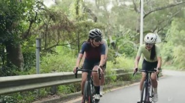 Kırsal yolda bisiklet süren genç Asyalı bisikletçiler