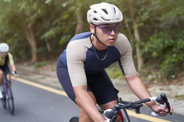 年轻的亚洲男子骑自行车骑自行车在乡间路上 — 图库照片