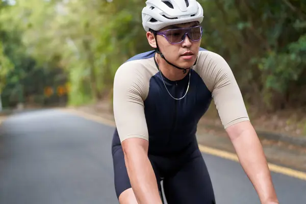 年轻的亚洲男子骑自行车骑自行车在乡间路上 图库图片