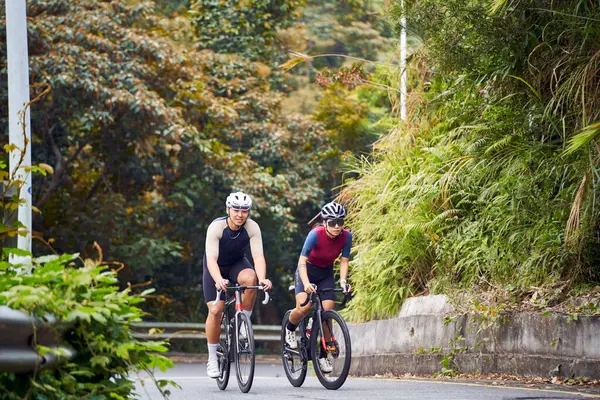 若いアジアのカップルの自転車に乗るサイクリスト 田舎の道路 ストック画像