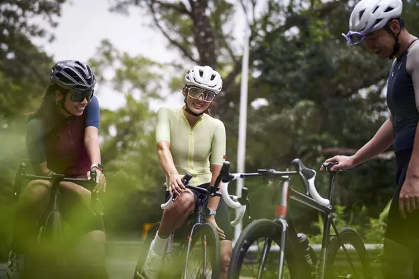 3人の幸せな若いアジアのサイクリストのグループは 屋外で自転車に乗っている間 会話をチャットします ロイヤリティフリーのストック写真