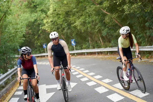 3人の若いアジアのサイクリストが田舎の道路で屋外で自転車に乗る ストックフォト