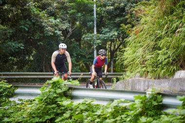 Kırsal yolda bisiklete binen genç Asyalı çiftler