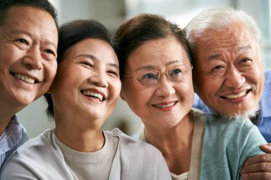 Mutlu Asyalılar. Aile kanepesinde oturan iki çift grup fotoğrafı çekiyor.