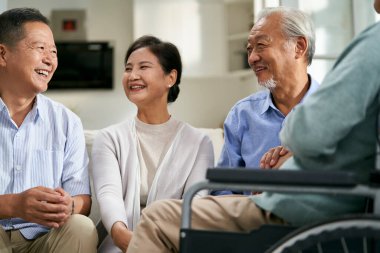 Bir grup mutlu Asyalı evde toplanıp güzel güzel sohbet ediyor.