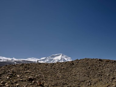 Fotoğrafçı mavi gökyüzünün altında dağ sırtında duruyor. Arka planda Cho oyu Dağı, Tibet, Çin.