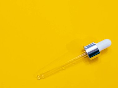 Parlak sarı arka planda kozmetik pipeti