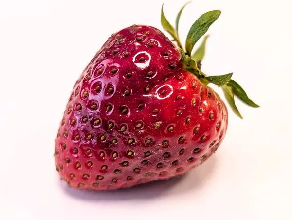 Beyaz arka planda olgun, sulu bir çileğin yakın plan görüntüsü.