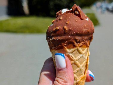 Çikolatalı dondurmalı waffle külahını tutan kadın.