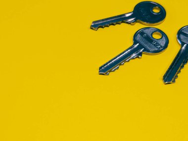 Parlak sarı arkaplanda kopyalama alanı olan üç metal tuş.