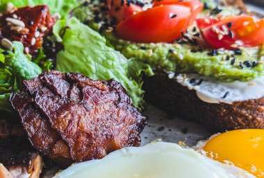 Avokado tostlu kahvaltı tabağı, kızarmış yumurta ve pastırma.