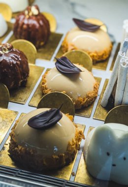 Kremalı kekler, hamur işleri ve çeşitli tatlılarla dolu rahat bir kafede fırın vitrini.