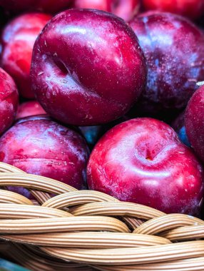 Çiftçi pazarındaki sepetin içindeki olgun eriklerin dikey yakın çekimi.