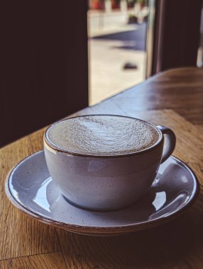 Kafe masasındaki seramik bardakta taze demlenmiş kapuçino.