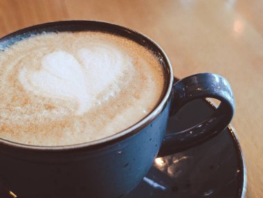 Kafe masasında seramik bardakta latte sanatıyla kapuçino, yatay sonbahar sahnesi