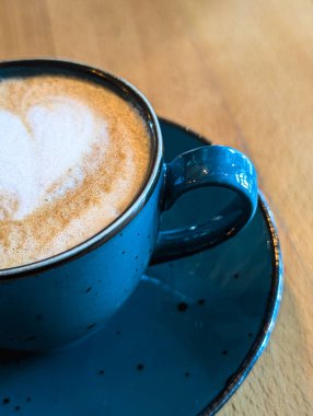 Kafe masasında seramik bardakta latte ile kapuçino.