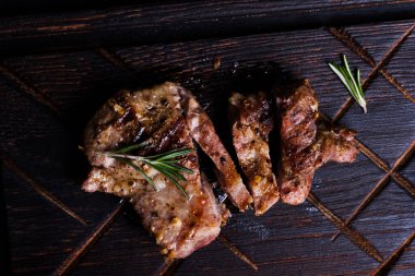 Sliced medium rare grilled steak with spices on wooden  board. Top view