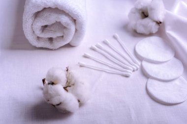 Clean towels, cotton pads and sticks and  cotton flowers on table. Natural cotton fabric texture