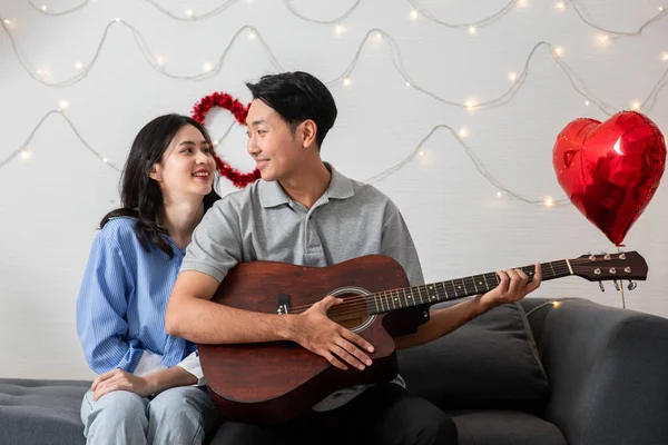 Couple of love playing on guitar for his cute lovely woman,Valentine's Day  concept.