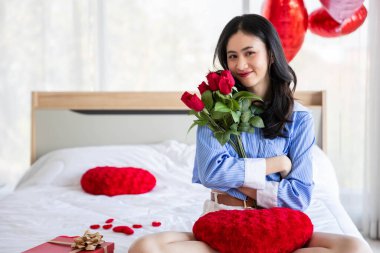 Smiling happy woman in love with gift box and rose in bedroom,Valentine's Day  concept.