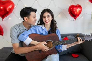 Couple of love playing on guitar for his cute lovely woman,Valentine's Day  concept.
