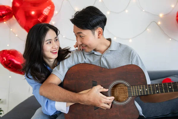 Couple of love playing on guitar for his cute lovely woman,Valentine's Day  concept.