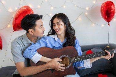 Couple of love playing on guitar for his cute lovely woman,Valentine's Day  concept.
