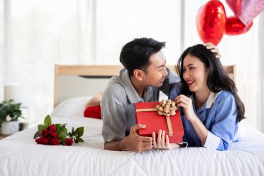 Beautiful young couple surprise with rose and gift in bedroom,Valentine's Day  concept.