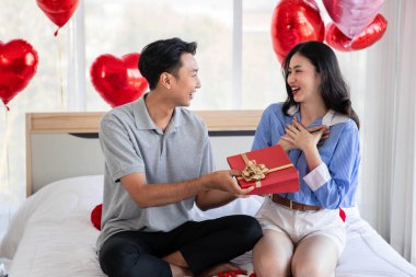 Beautiful young couple surprise with rose and gift in bedroom,Valentine's Day  concept.