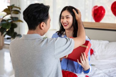 Beautiful young couple surprise with rose and gift in bedroom,Valentine's Day  concept.