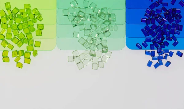 透明的绿色和蓝色塑料树脂颗粒与它的彩色样品板 图库照片