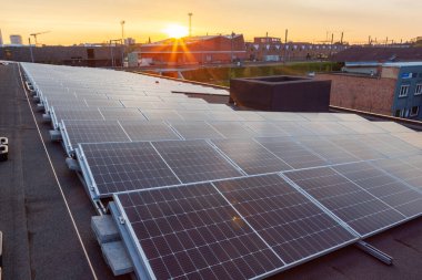 Konut alanındaki bir binada güneşli bir günde çatıda güneş panelleri var.