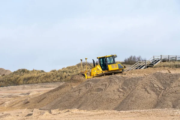 This Bulldozers earthmoving machinery is moving sea sand on the beach on a sunny day