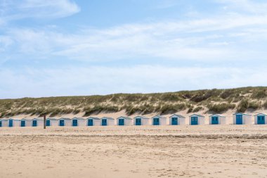 Deniz kenarında yan yana bir sıra plaj kulübesi var.