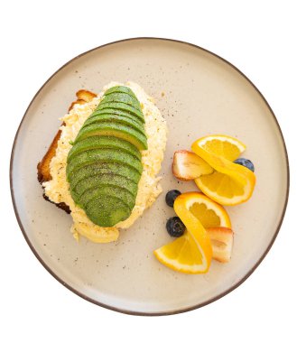 Çırpılmış yumurtalarla kaplanmış avokado tostu portakal, çilek ve yabanmersinli taze meyve ile servis edilir.