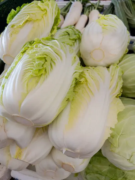 stock image Close-up of fresh Napa cabbages neatly stacked, showcasing their crisp leaves and fresh quality at a local market