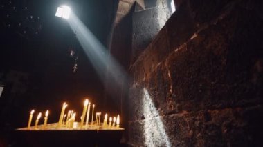 Aragatsotn Eyaleti, Ermenistan, 24 Nisan 2022 - Hovhannavank Manastırı 'nın eski penceresinden güneş ışınları ve iç kısımları aydınlatan bir sürü mum