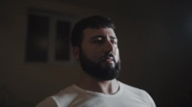 Güçlü bir adamın vücut kaslarını şişirdiği, spor salonunda büyük ağırlıklarla dramatik ışıklandırma yaptığı el kamerasıyla. Spor salonunda güçlü bir adamı vurmak..